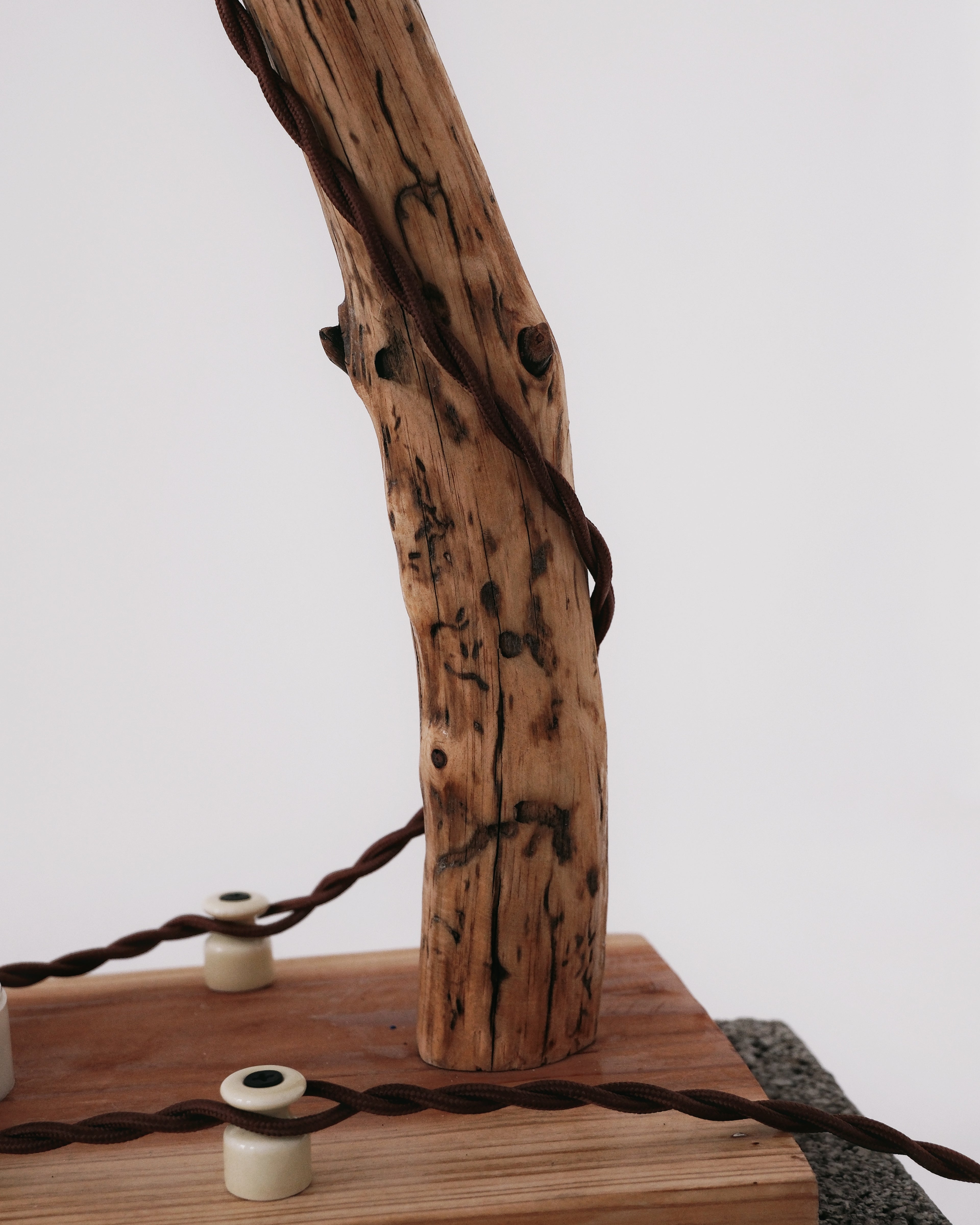Wooden branch with twisted rope on a wooden block against a white background