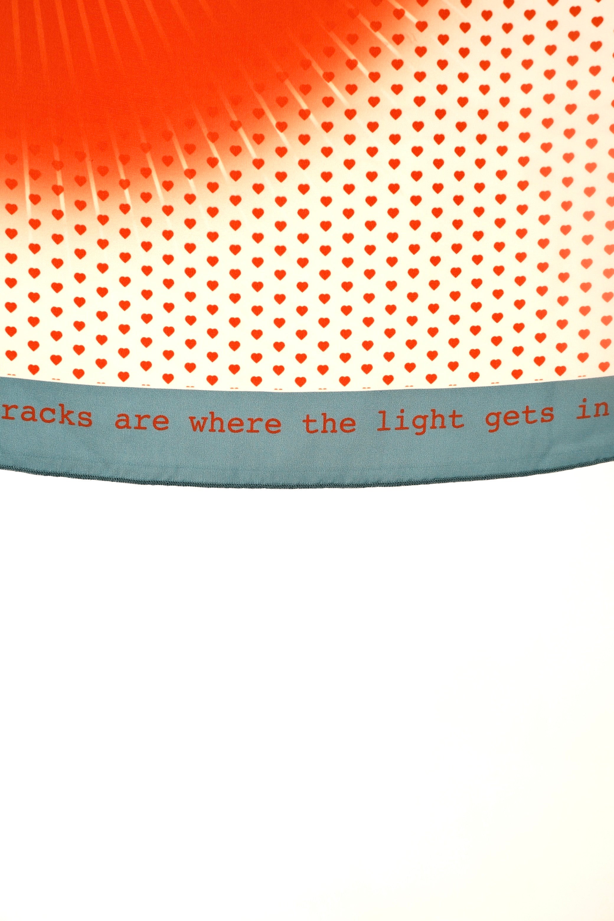 Scarf from DAE with heart pattern and text 'tricks are where the light gets in' on a white background