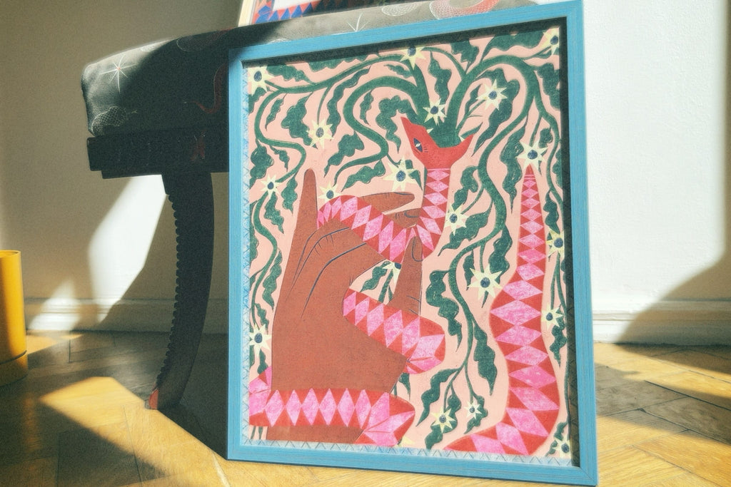 A colorful poster featuring an artistic depiction of a serpent with abstract and cultural elements, displayed on a flat surface with natural lighting. Poster “Serpent” by Feli Beringer – symbolic wall art print from DAE • დაე, representing empowerment and transformation.