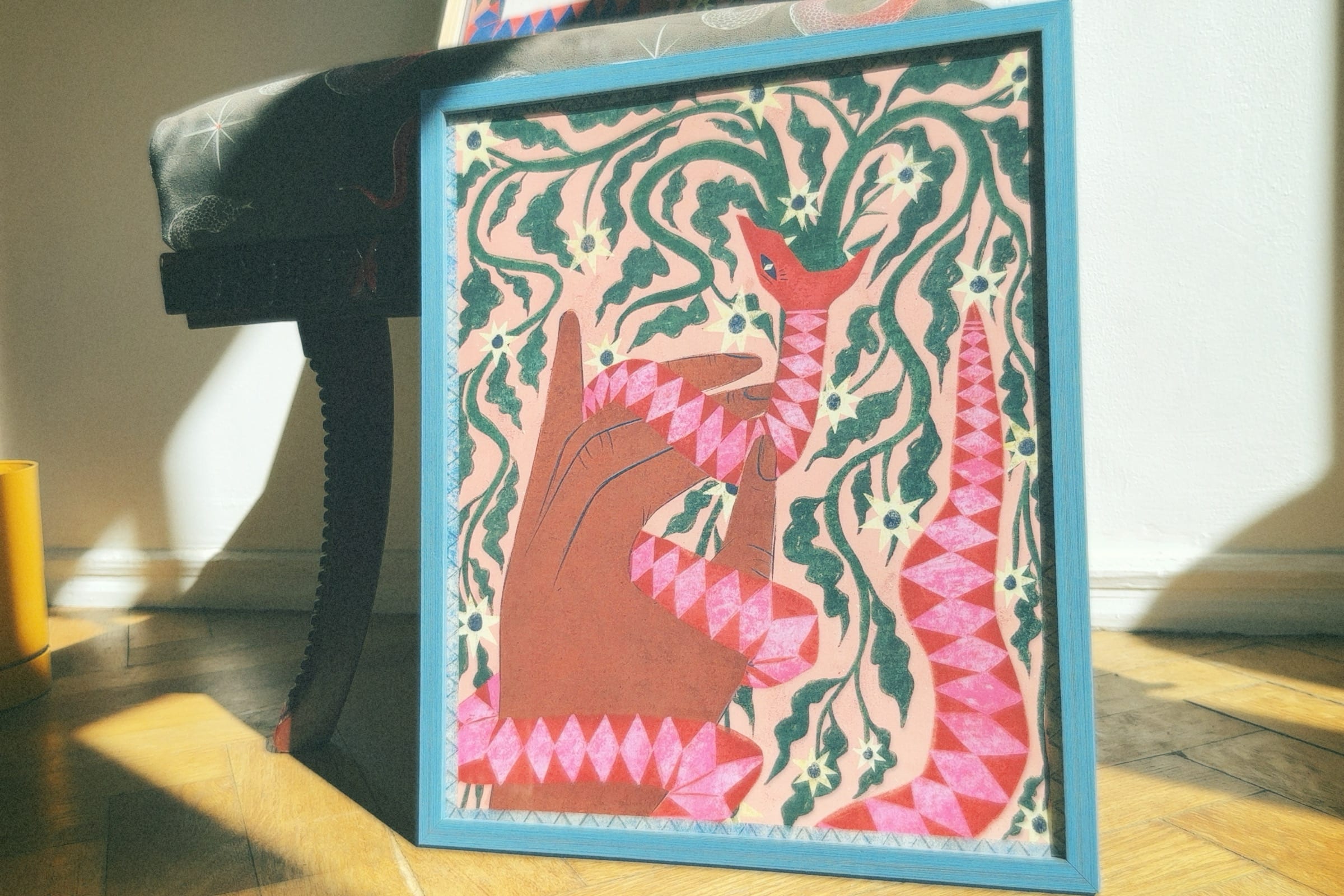 A colorful poster featuring an artistic depiction of a serpent with abstract and cultural elements, displayed on a flat surface with natural lighting. Poster “Serpent” by Feli Beringer – symbolic wall art print from DAE • დაე, representing empowerment and transformation.