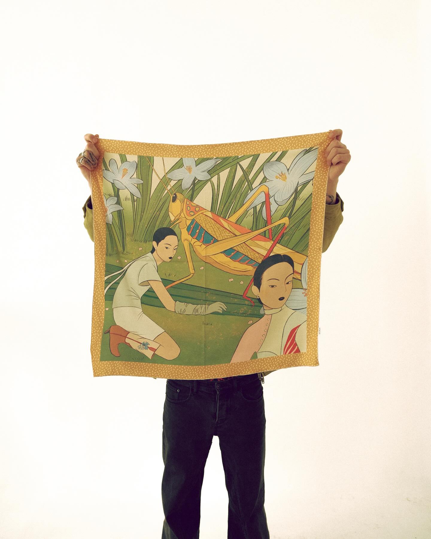 Person holding a colorful fabric with an illustration of two people and nature elements.