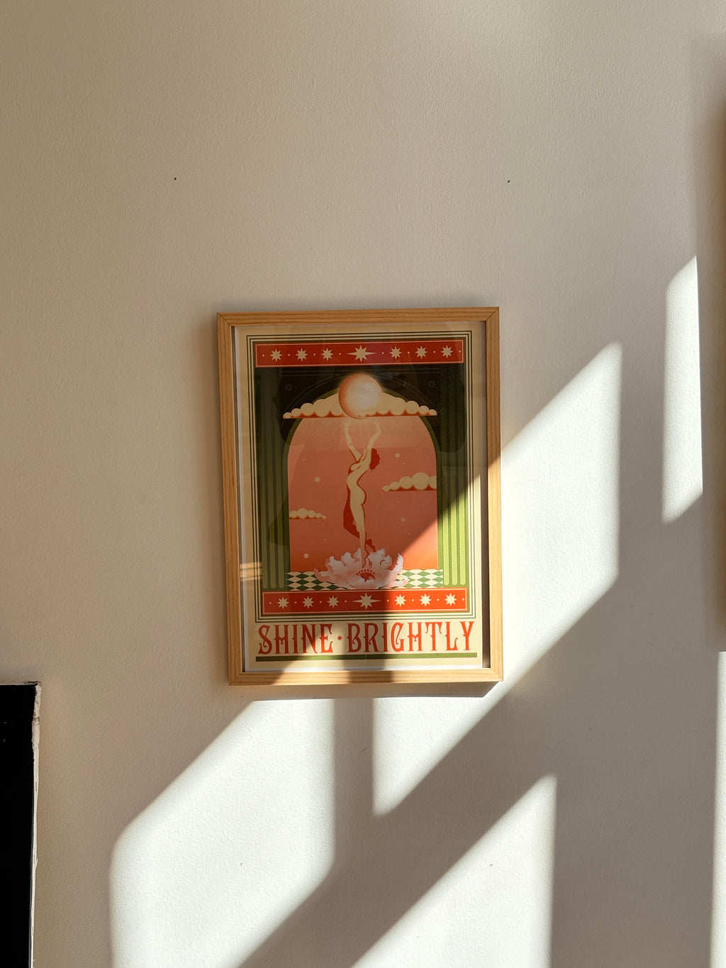 Framed “Shine Brightly” poster by Bianca Roberts x DAE featuring a feminine figure rising toward the sun in warm tones