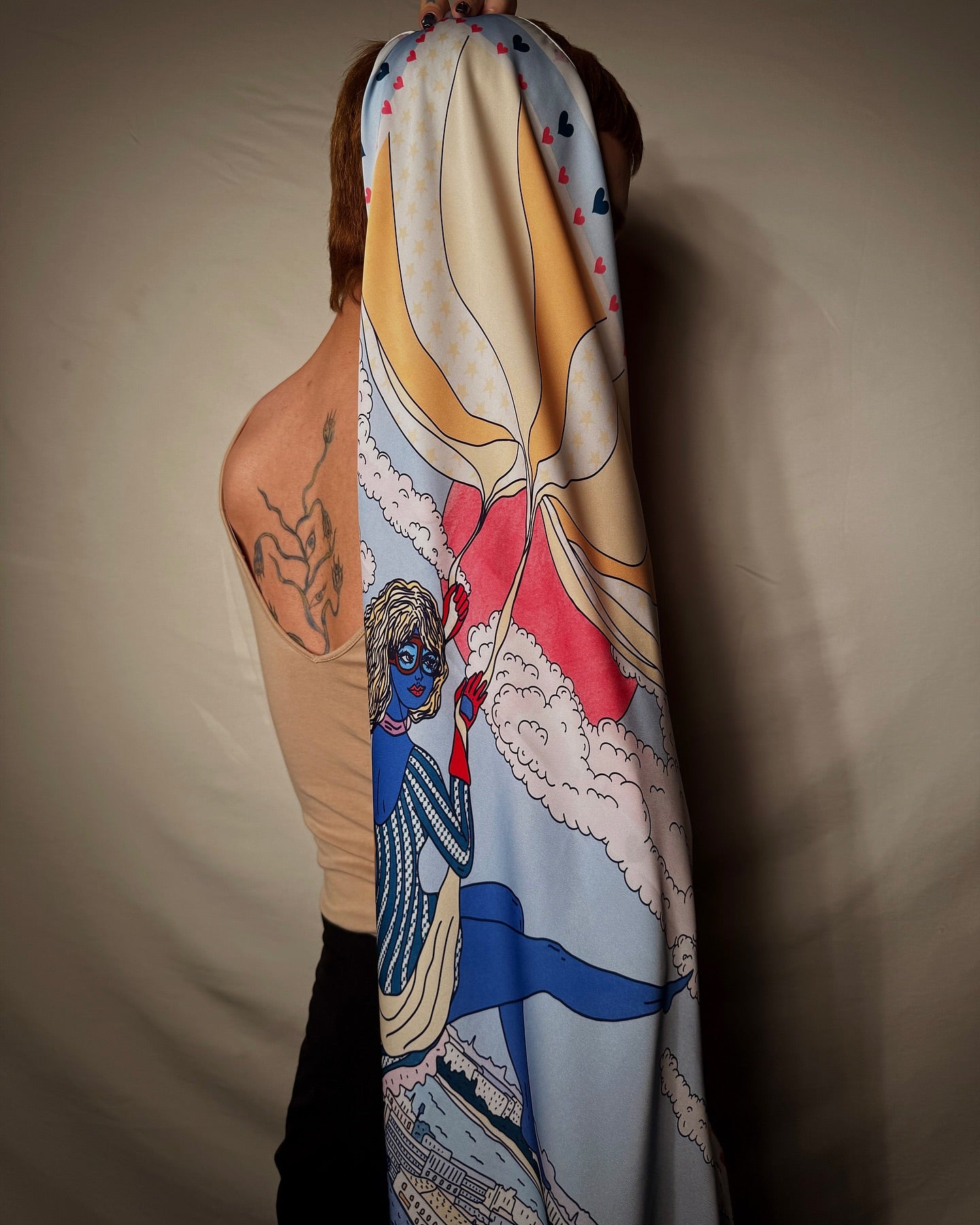 A scarf with a colorful design featuring illustrations of characters and abstract shapes wrapped around a person.