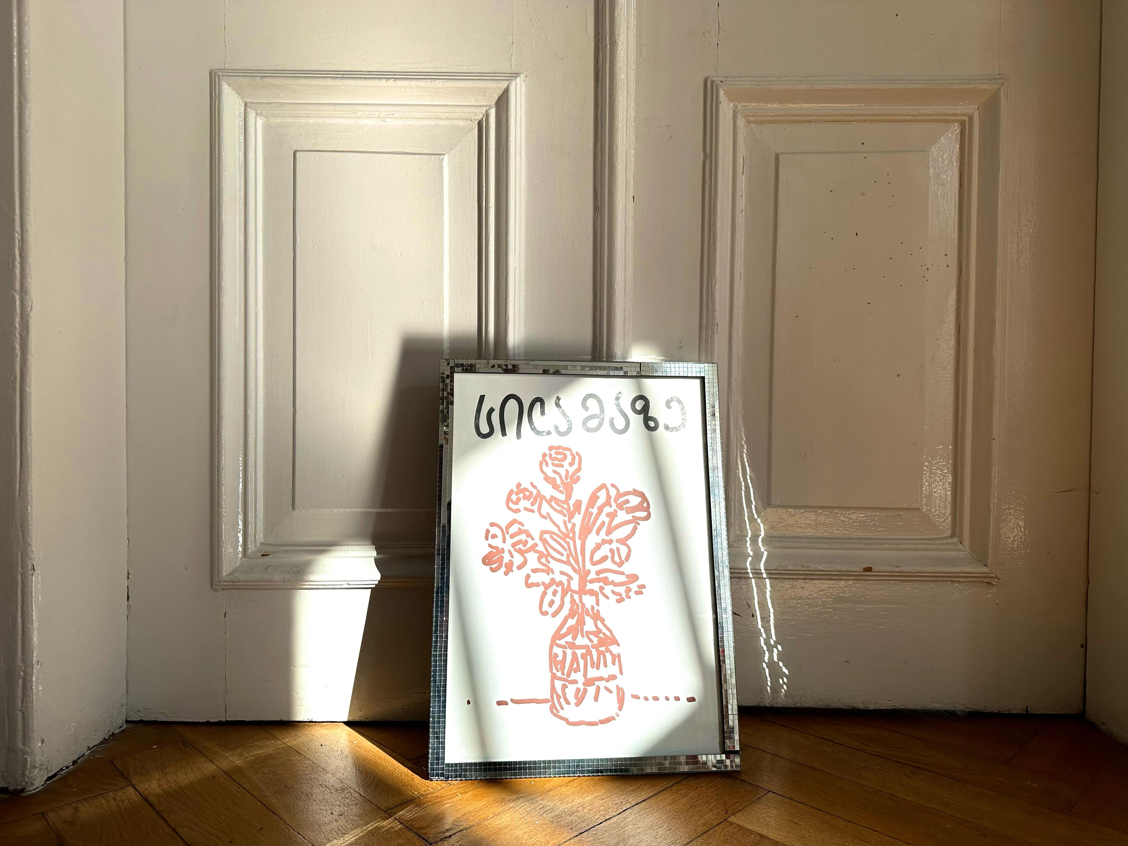 A poster with a red floral illustration leaning against a door, showcasing clean lines and refined details.