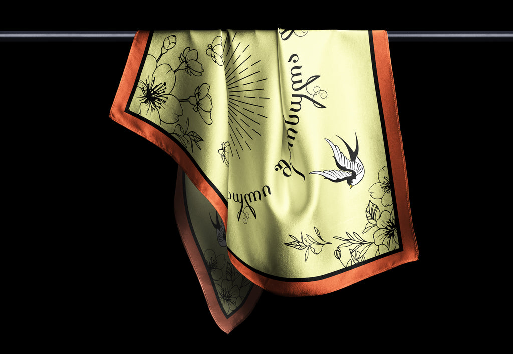 A scarf with a floral and musical theme, predominantly yellow and orange with darker patterns.