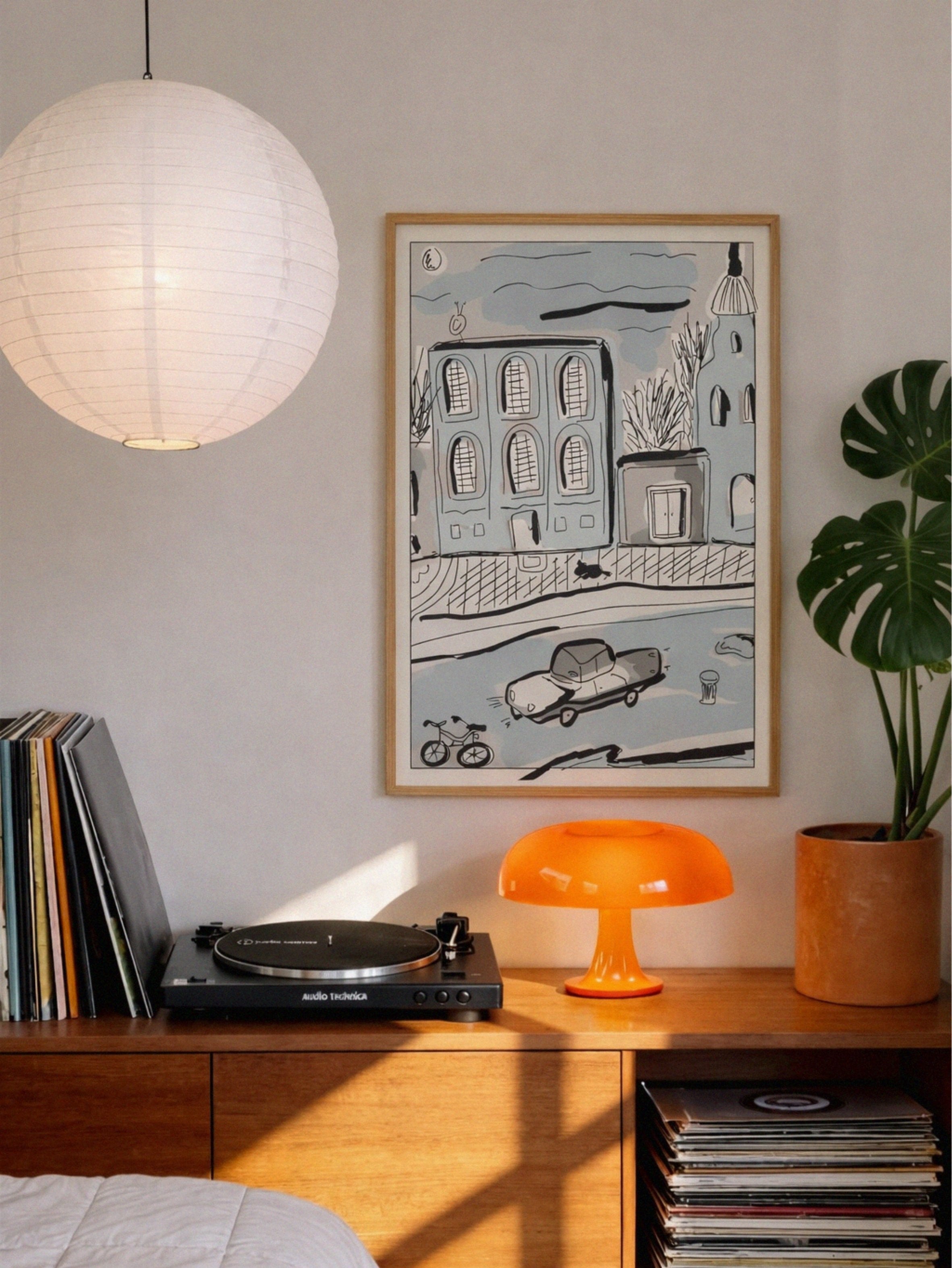 Turntable on a wooden console with vinyl records, framed artwork, and a lamp in a cozy room.