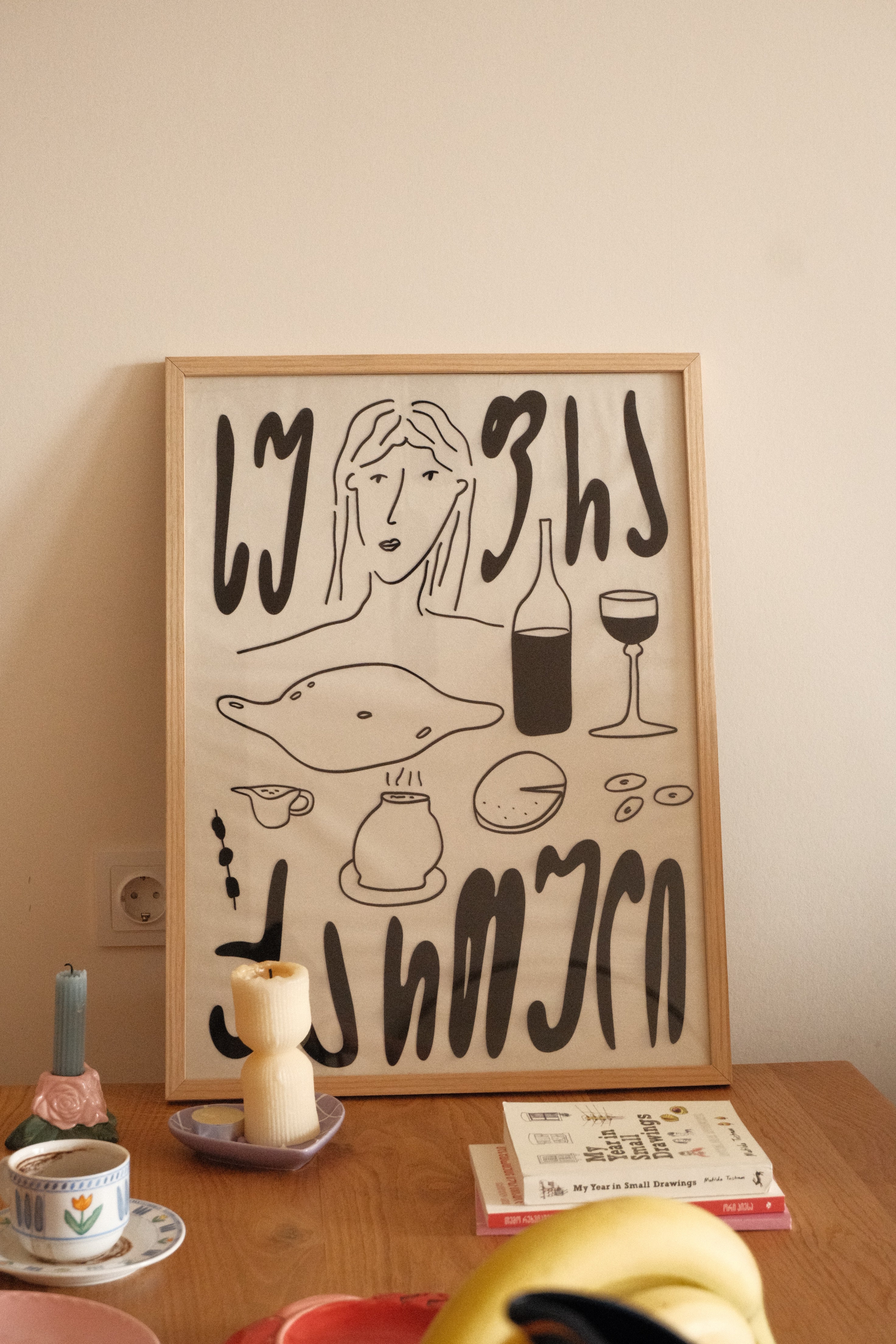 Framed abstract artwork on a wall with a candle and decorative items below.