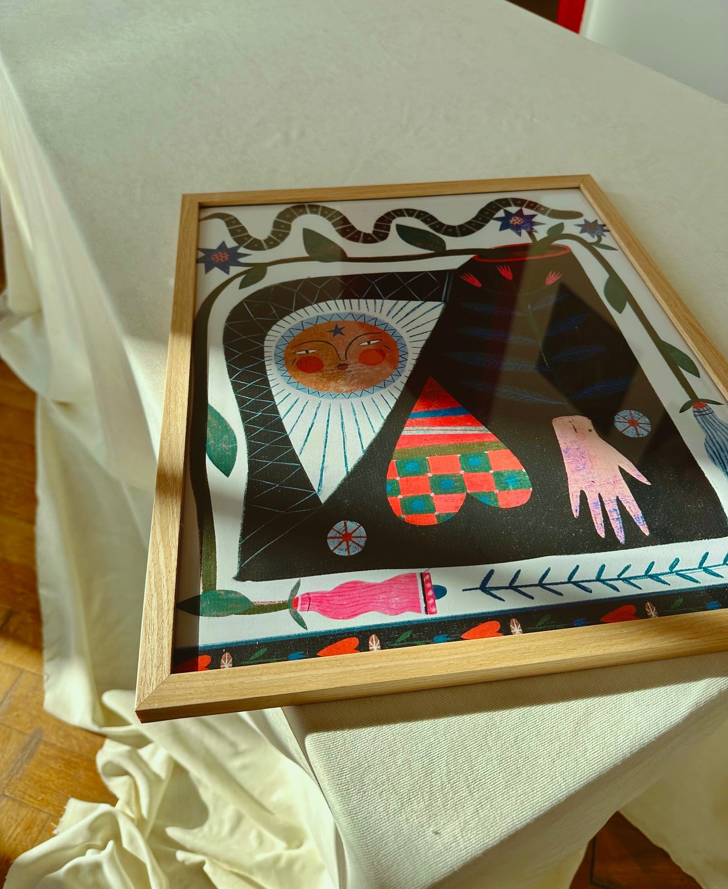 A colorful poster featuring abstract characters and shapes displayed on a table with a light-colored tablecloth.