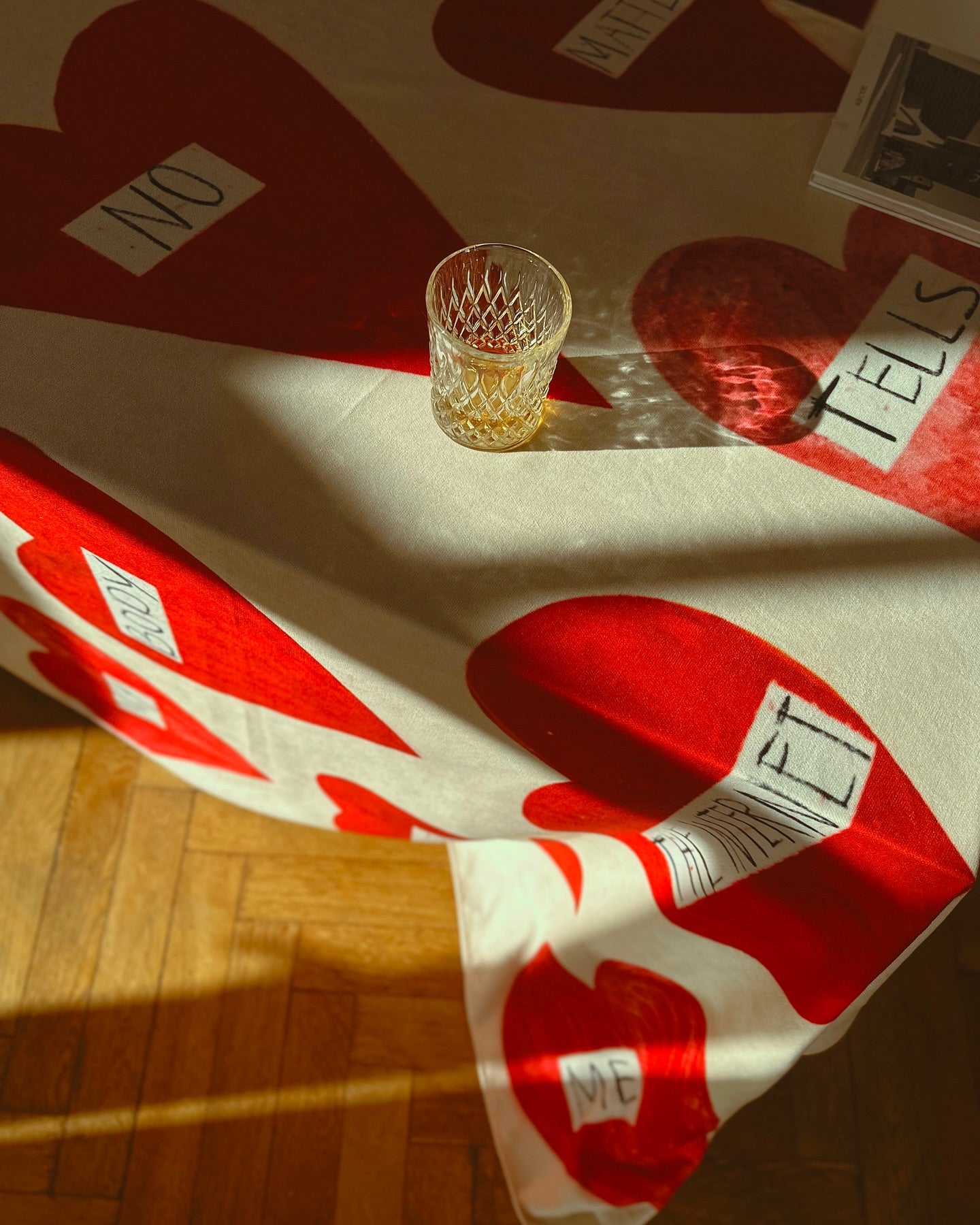 Glass of whiskey on a tablecloth with heart shapes and text