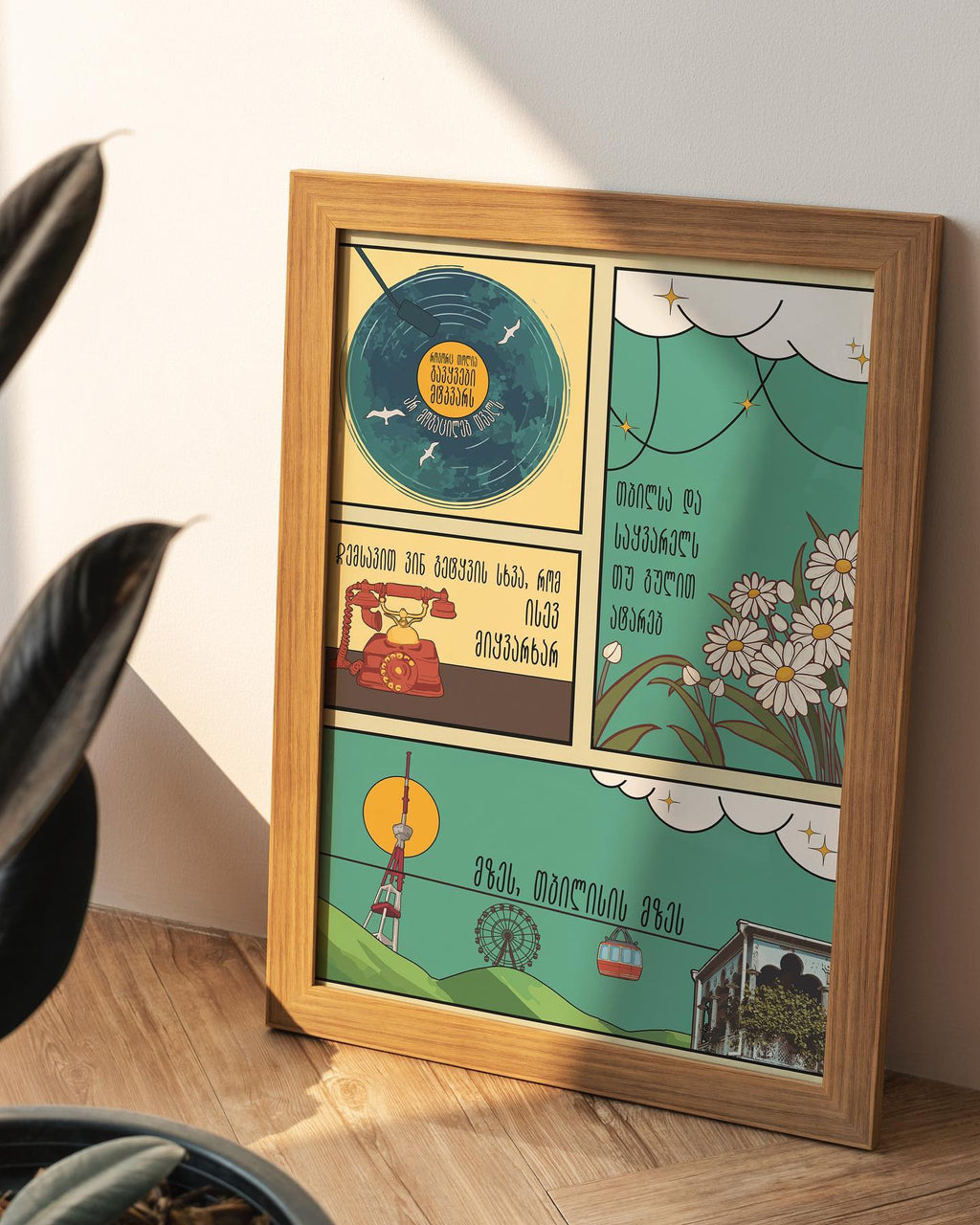 Illustrated “The Tbilisi Sun” poster by Mariam Kantaria in a wooden frame, displayed against a white wall with warm lighting.
