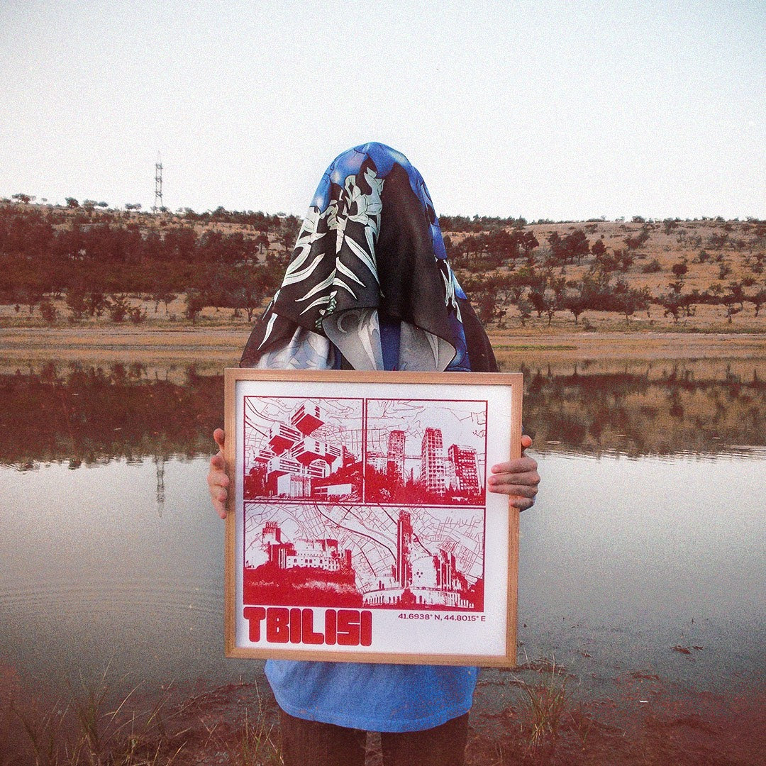 Person holding a framed print of Tbilisi by a lake