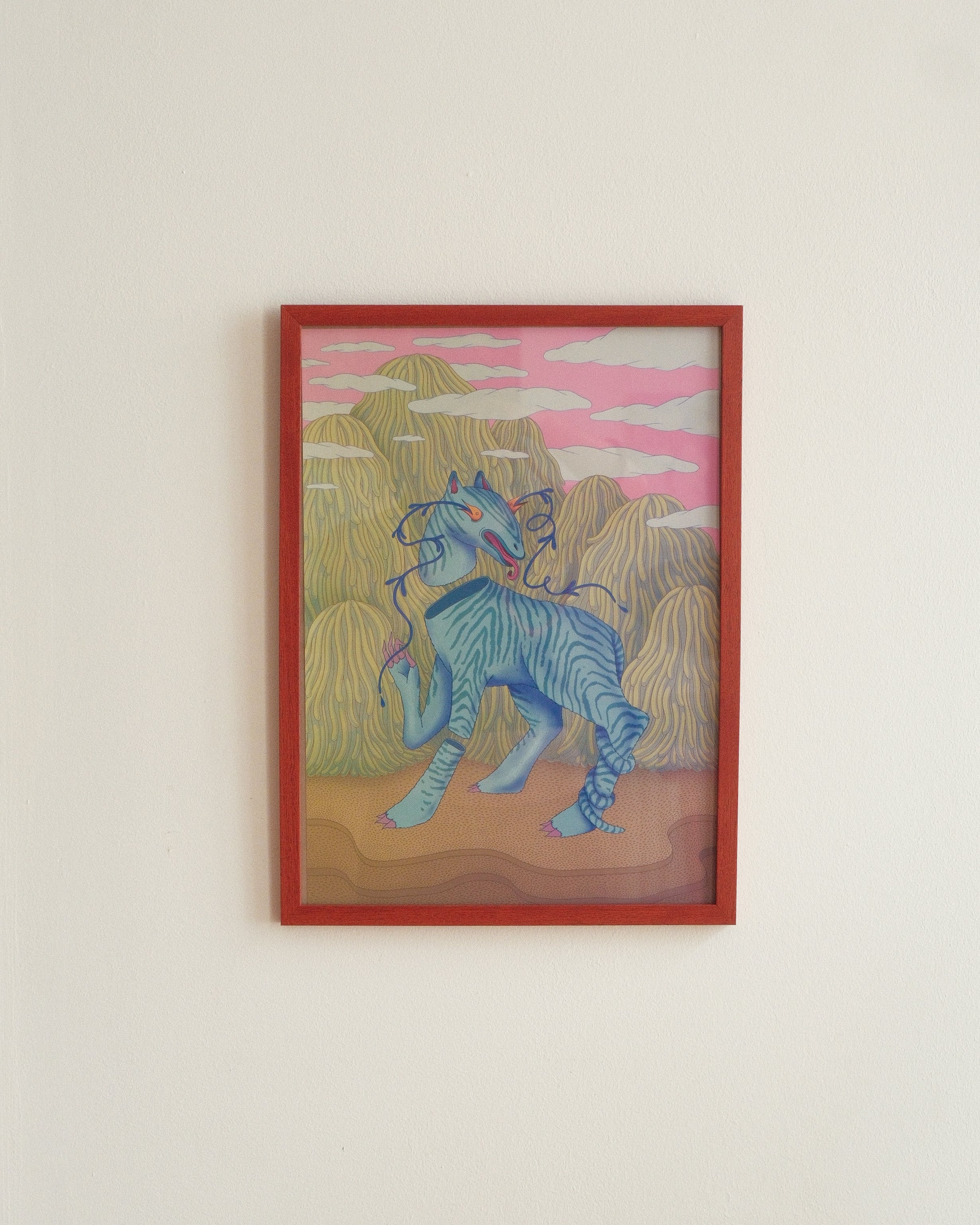 Framed artwork of a blue creature in a desert landscape with a red frame.
