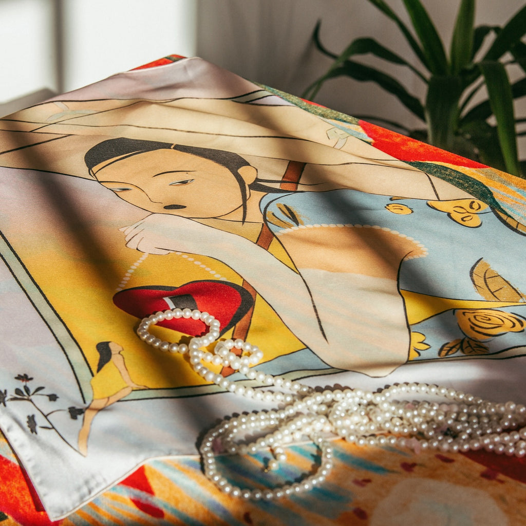 A silk scarf with an illustration featuring a woman and various objects, predominantly in pastel colors, with a strand of pearls lying on the scarf. Art silk scarf featuring poetic illustration by Lea Woo