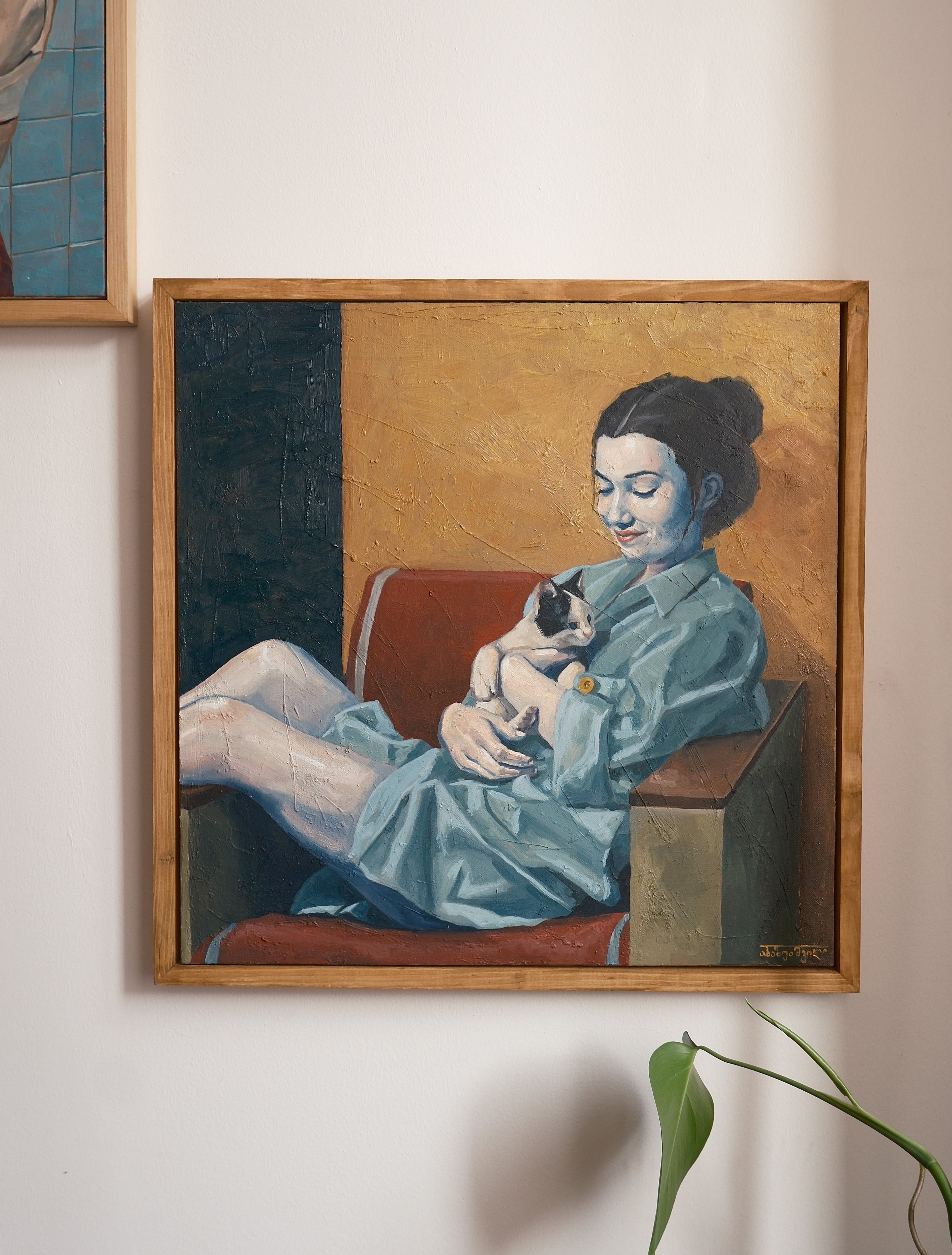 Framed painting of a woman holding a cat on a wall.