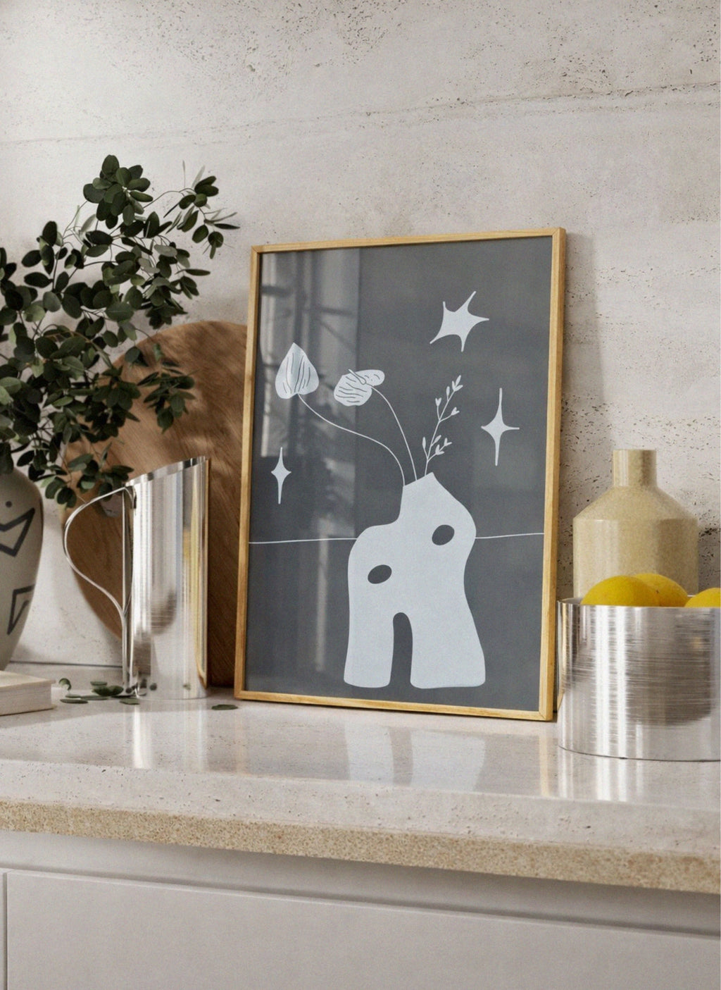 Framed artwork with a white abstract design on a shelf with decorative items.