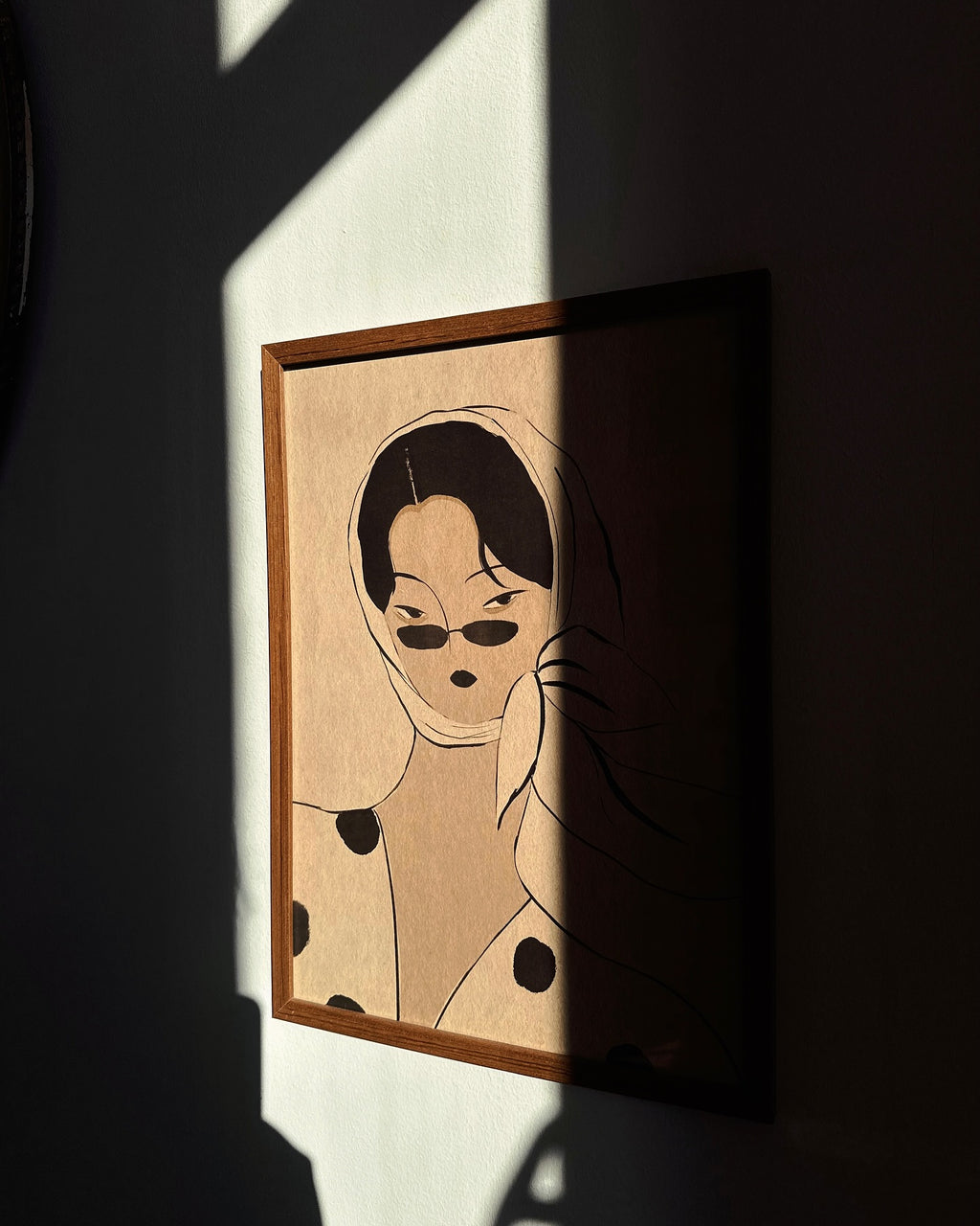 Framed “Vintage” poster by Lea Woo x DAE hanging on a wall in soft sunlight, featuring a woman in calm tones