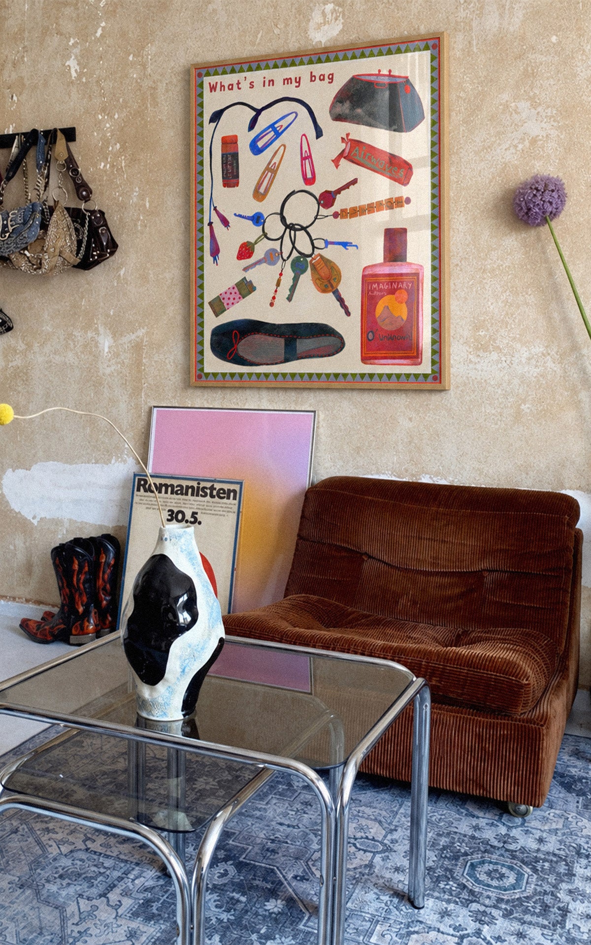 “What's in My Bag” poster by Feli Beringer for DAE, featuring colorful everyday objects in a light wood frame above a brown armchair.