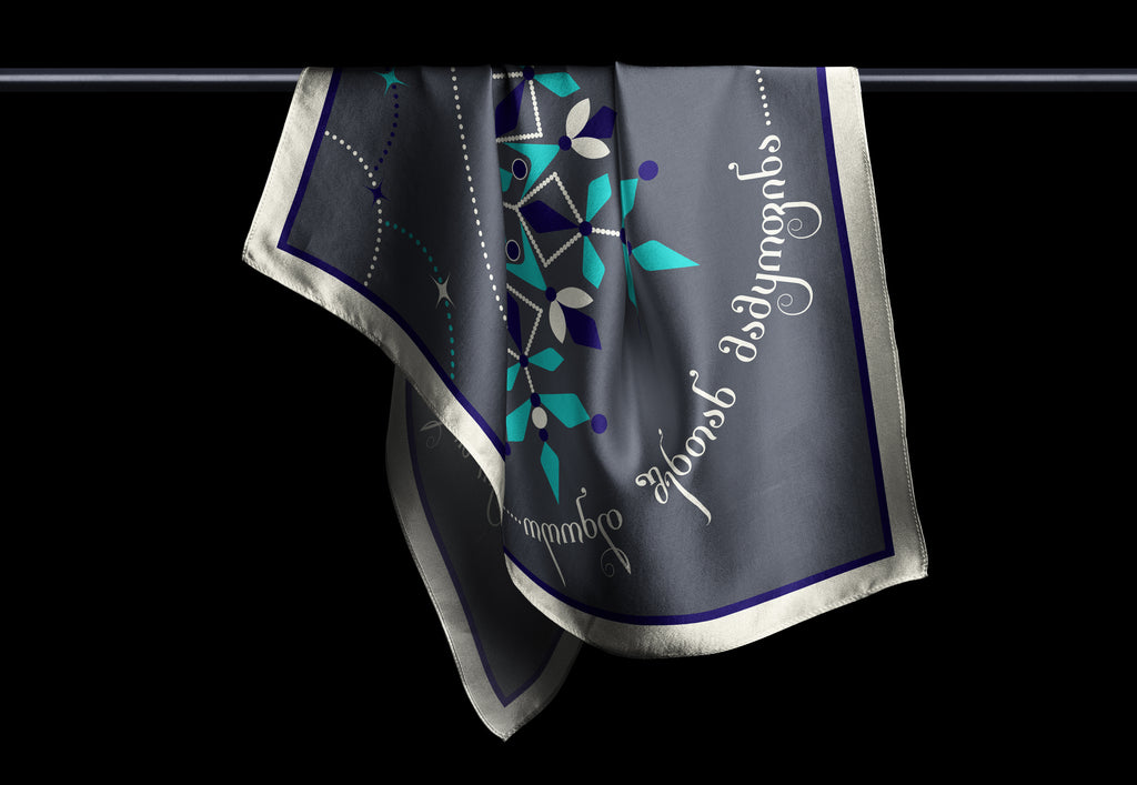 A Georgian Frost Sonata scarf in gray, blue, and silver, featuring a floral pattern and textual details.