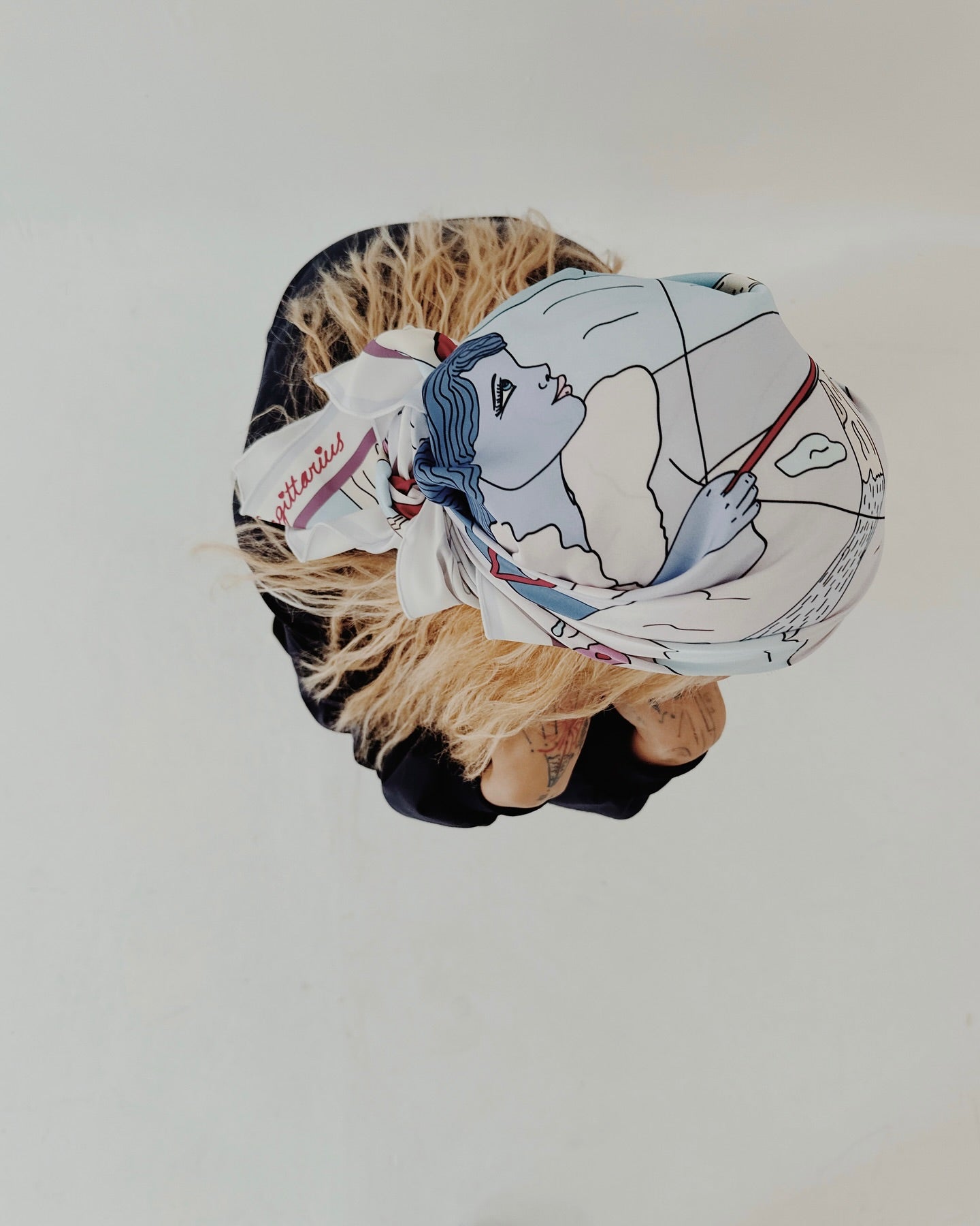 A silk scarf with an artistic illustration predominantly in blue and white colors, depicting a stylized version of the Sagittarius zodiac sign.